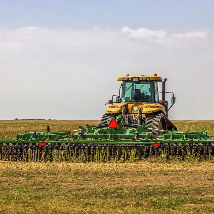 Machine agricole en pleine récolte de céréales en Bretagne, illustrant l’activité de négoce de céréales et d’engrais adaptée aux besoins des agriculteurs locaux.